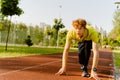 Concentrated man getting ready to run on sports track in park Royalty Free Stock Photo