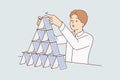 Concentrated man makes pyramid of playing cards symbolizing fragile business structure