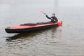 Concentrated man with oar in hands rowing boat in river in cold autumn day, water sport, guy wearing grey cap and and black jacket Royalty Free Stock Photo