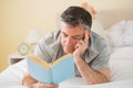 Concentrated man reading a book on his bed Royalty Free Stock Photo