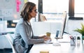 Concentrated mature business woman working with computer while drinking coffee in the office