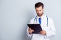 Concentrated medico in uniform holding clipboard and reading inf Royalty Free Stock Photo