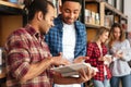 Concentrated men students standing in library reading book. Royalty Free Stock Photo