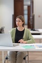 Focused middle-aged female student working on laptop in coworking space, getting second degree