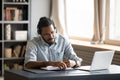 Concentrated biracial guy listening to favorite music while planning workday. Royalty Free Stock Photo