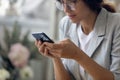 Concentrated millennial female in glasses holding smartphone making answering call