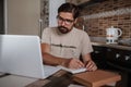 Concentrated millennial hipster guy wearing glasses, listening to favorite music while planning workday Royalty Free Stock Photo