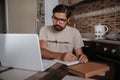 Concentrated millennial hipster guy wearing glasses, listening to favorite music while planning workday Royalty Free Stock Photo