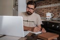 Concentrated millennial hipster guy wearing glasses, listening to favorite music while planning workday Royalty Free Stock Photo