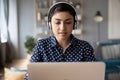 Millennial Indian girl in headphones study on laptop