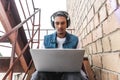 concentrated mixed race male freelancer in headphones working with laptop