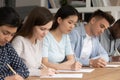 Concentrated mixed race students passing evaluation examination during session.