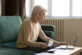 Contemporary elderly woman pay bills online on laptop