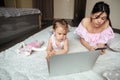 Concentrated mother chatting by phone while her daughter using laptop Royalty Free Stock Photo