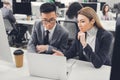 Concentrated multiethnic businessman and businesswoman discussing work and pointing at laptop Royalty Free Stock Photo