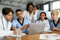 Concentrated multiethnic team of doctors sitting at table, using laptop Royalty Free Stock Photo