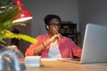Concentrated pensive African American man student looks at laptop sits at computer in home office