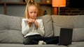 Concentrated pupil girl making homework at copybook on cosy sofa writing math tasks of elementary school subjects Royalty Free Stock Photo