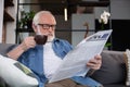 Concentrated retired man reading newspaper with coffee