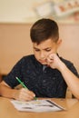 Concentrated schoolboy sitting at desk and writing in exercise book. Learning concept Royalty Free Stock Photo