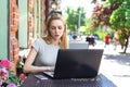 A concentrated Self employed Caucasian woman working with her phone and laptop in a restaurant terrace Royalty Free Stock Photo