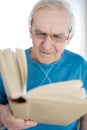 Concentrated senior man reading book at home