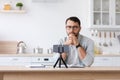 Concentrated serious adult caucasian male teacher with beard in glasses watching to phone