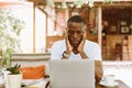 Serious multiracial businessman using laptop in cafe with head in hands in cafe. Video call and read finance information Royalty Free Stock Photo