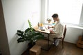 Young blonde man using laptop and taking notes at home in the living room Royalty Free Stock Photo