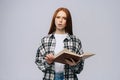 Concentrated serious young woman college student holding opened books and looking at camera Royalty Free Stock Photo