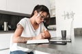 Concentrated serious young woman using laptop computer writing notes. Royalty Free Stock Photo