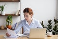 Concentrated serious young woman working with business document and laptop Royalty Free Stock Photo