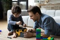 Concentrated small boy fixing car with caring dad.