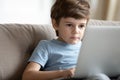 Smart little boy using laptop at home