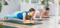 Young woman holding plank pose on forearms in yoga studio