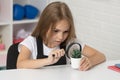 concentrated teen girl looking at plant through magnifying glass, knowledge