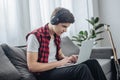 concentrated teenager with headphones playing game on laptop while sitting