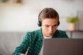 Concentrated teenager using laptop, sitting at home alone