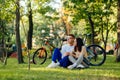 Concentrated thoughtful couple of cyclists are having rest in the city park, sitting on a lawn and looking far ahead. They are Royalty Free Stock Photo