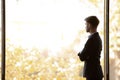 Concentrated thoughtful young businessman looking away at panoramic office window. Royalty Free Stock Photo