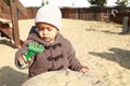 Concentrated toddler boy playing with rake in sandbox on kids playground