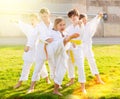 Tween girls and boys exercising taekwondo techniques on green lawn