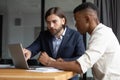 Concentrated two mixed race coworkers discussing presentation on laptop. Royalty Free Stock Photo