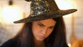 Concentrated witch in hat conjuring, black magic, costume Halloween party