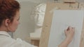 Concentrated woman artist painting plaster bust in art studio