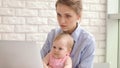 Concentrated woman with baby working on laptop. Business woman working Royalty Free Stock Photo