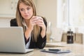 Concentrated woman looking at laptop with coffee in hand