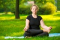 Concentrated woman oversize meditates on the lawn in the park in the lotus