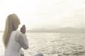 Woman prays meditating in front of a ocean view