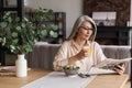 Concentrated woman reading newspaper while drinking juice